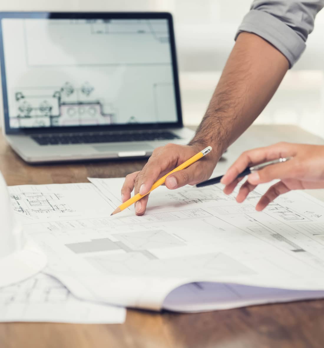 Reviewing architectural blueprints on desk with laptop